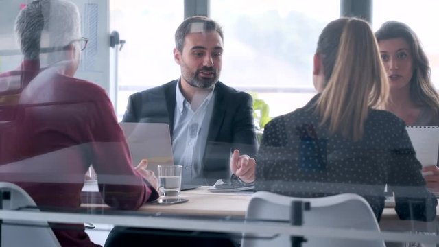 Video of business people discussing together in conference room during meeting at office.