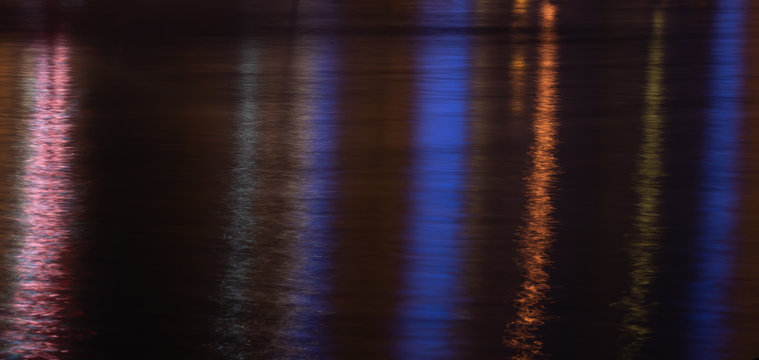 Colorful light reflection on the water surface at night.