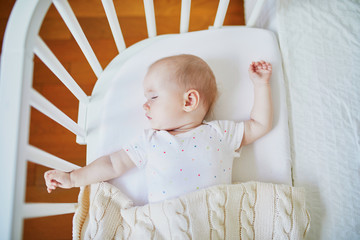 Baby sleeping in co-sleeper crib attached to parents' bed