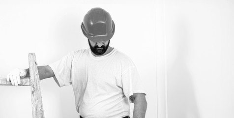 Bearded painter in safety helmet. Home renovations service. Painter man at work. Handyman with a tool belt.