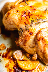 Grilled chicken on the pan with spices, garlic, thyme and lemon slices. Selective focus. Shallow depth of field.