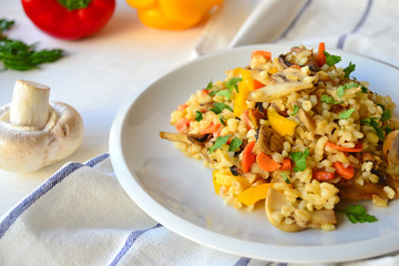 Bulgur with vegetables on a white plate on a kitchen table.