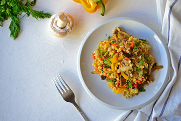 Bulgur with vegetables on a white plate on a kitchen table.