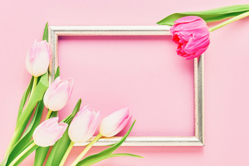 Golden frame with pink tulips on pink background. Mockup. Top view, copy space.