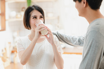 Asian pregnancy woman drinking milk from her husband. Couple, Motherhood, mom and kids, family relationship, new born baby, healthy pregnancy concept.