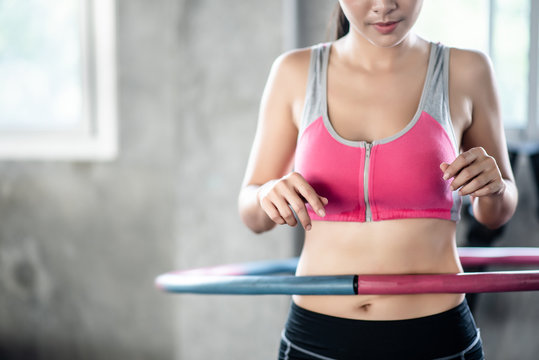 Young Woman Ratating Hoola Hoop In The Gym