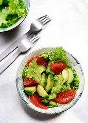 Avocado grapefruit salad with lettuce in a bowl on grey metal background. Raw vegetarian detox salad, healthy food. Selective focus