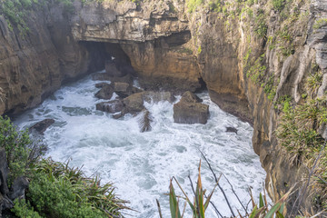 froth and cliffs at narrow inlet of Tasman sea shore, Punakaiki, West Coast, New Zealand