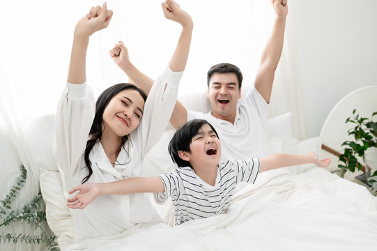 Very Happy Family Mom, Dad And Son Are Wake Up Together With Fresh Smile Powerful Stretching Gesture. Love In Home, Warm Family, Parenthood, Good Lifestyle Concept.