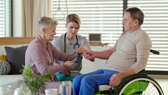Healthcare worker visiting senior patient in wheelchair at home.