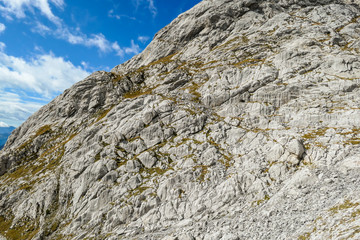 A close up shot of a massive mountain range in Austrian Alps. The rocky mountain looks inaccessible. High Alpine mountaineering. Sun rays coming from above the peaks.