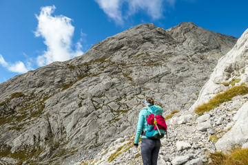 Fototapeta premium A woman reaching the top of Monte Coglians, Hohe Warte on the Austrian-Italian Alpine border. Very steep and narrow pathway that she walks on. She is not giving up, visible goal. Stunning view