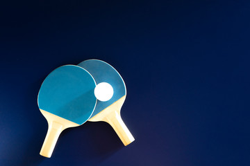 Table tennis rackets and white tennis ball lie on a bright multicolored background