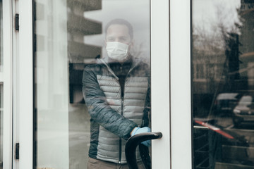 Covid-19 outbreak themed image. Male with mask and gloves leaving his home in quarantine time. Stay at home. 