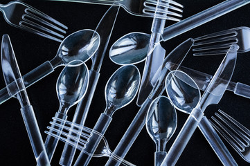 Plastic cutlery on a black grainy background. The concept of recycling and ecology.