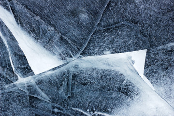 Abstract textured background of cracked ice in the thaw, closeup, environmental, ecological and climate change concept