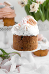 Easter cake kulich. selective focus Traditional easter sweet bread decorated with meringues and macaroons on a plate on a background of a vase with white tulips. Copy space