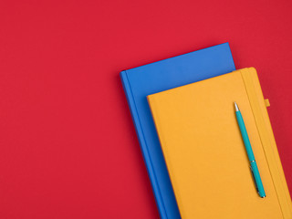 Bright business notebooks and pen on red background.