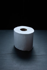 Single roll toilet paperl roll on dark background