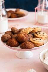 Cookies on a white plate with milk on a pink background.