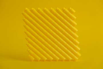 Yellow plastic building blocks in the shape of a cube on yellow background. Background of plastic details building blocks. Parts of bright small spare parts for toys. Copy, empty space for text