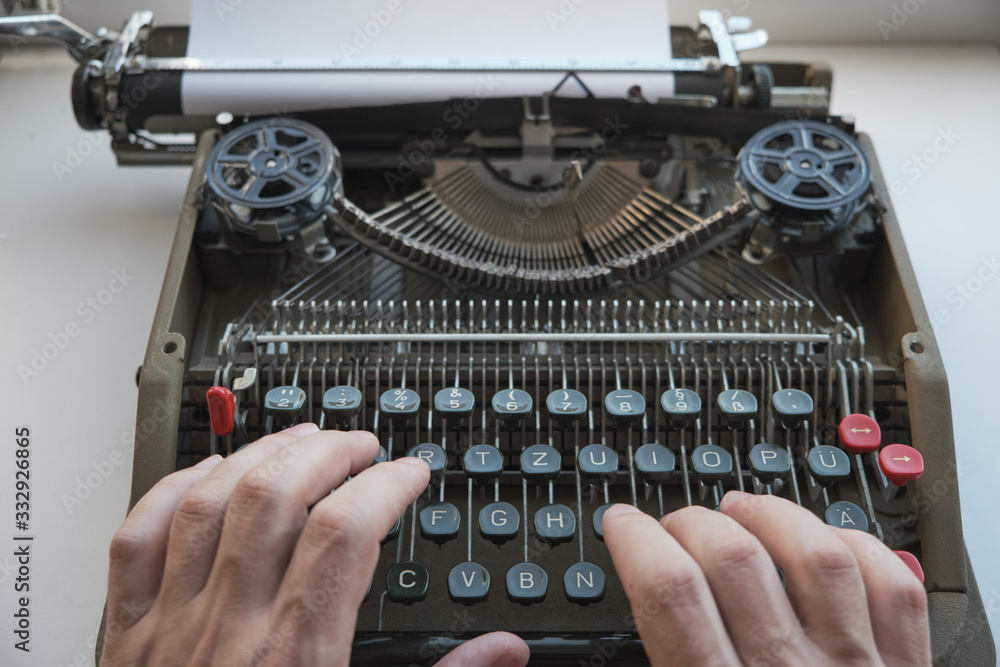 Fototapete fingers type text on the keyboard of an old retro mechanical typewriter.