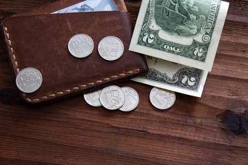 Paper two-dollar bill with scattered metal rubles on a wooden table.