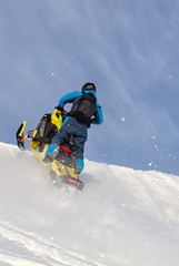 Fototapeta na wymiar jump on a mountain snowmobile from a high ledge with the descent of a large avalanche. snowmobilers sports riding. Winter extreme. testing of a new model of mountain snowmobile, prototype 2021