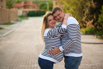 Happy pregnant woman and her husband kissing and hugging, posing on the street.