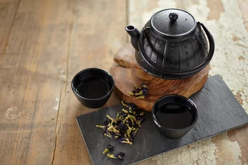 Foto op Aluminium Herbal asian tea on vintage wooden table. Top side view of teapot and cups on black rock with copy space © strixcode