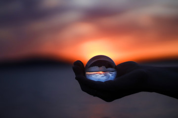 glass ball in hand in sunset 