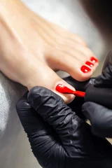 Rolgordijnen Handen schilderen teennagels in het rood. © okskukuruza