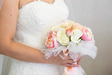 The bride holds a beautiful wedding bouquet of pink and white flowers in her hands