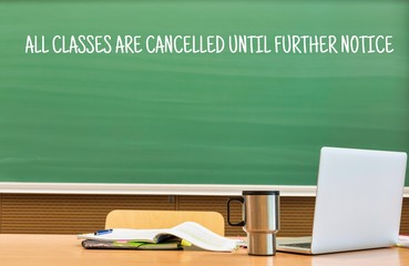 University lecture hall with green chalk board reading all classes are cancelled until further...