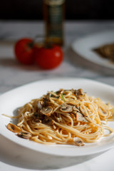 pasta with mushrooms on a white plate on a light background close-up. lunch spaghetti with tomatoes