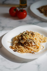 pasta with mushrooms on a white plate on a light background close-up. lunch spaghetti with tomatoes