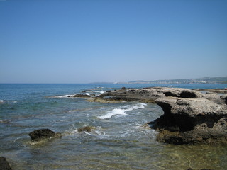 Weak waves gently wash the stones lying on the shallow bottom of the sea rocky shore in good weather.