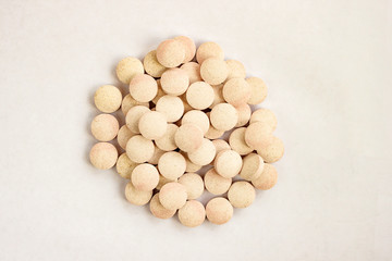 Medical lozenges for relief cough, sore throat and throat irritation on white background. Herbal candy. Pink beige color tablets. Close up top view. Selective soft focus. Text copy space.