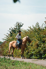 Portrait of young brunette woman in a white shirt and helmet on a horse