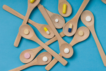 Medical background . Wooden spoon with pills or capsules.