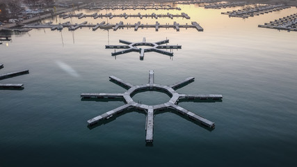 Wide angle shot of circular empty boat docks with early morning sunrise reflecting off calm lake water in Chicago Illinois