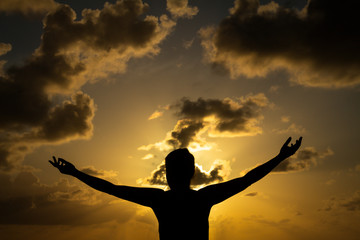 Figure of a woman's body with arms outstretched during sunrise. Raise your arms to the sky. Hope or happiness concept.