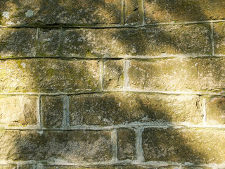 Old stone wall with sunbeams, oblong stones, sunny day, sun shine