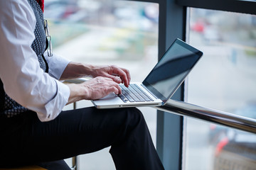 Adult male businessman, teacher, mentor working on a new project. Sits by a large window on the...