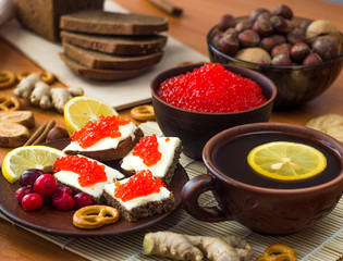 Sandwiches with butter and red caviar are on the plate. Next to it is a Cup of tea with lemon.