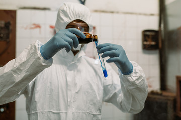 Scientist doctor biologist in hazmat suit and protective respiratory mask working in laboratory...