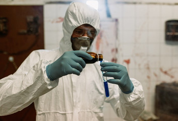 Scientist doctor biologist in hazmat suit and protective respiratory mask working in laboratory...