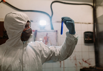 Scientist doctor biologist in hazmat suit and protective respiratory mask working in laboratory...