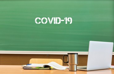 Photo of laptop on professor desk with the text saying Covid 19 on it