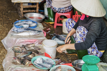 Asian woman cutting cleaning and selling fresh fish in market